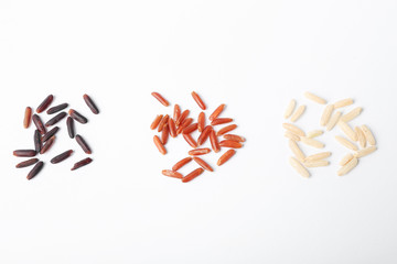 Different types of uncooked rice on white background, top view