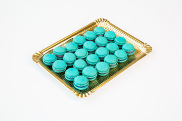 blue macaroons on a gold tray with white background