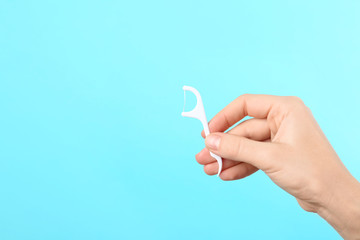 Woman holding dental floss pick on color background, space for text. Mouth and teeth care