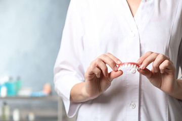 Dentist holding teeth cover on blurred background, closeup. Space for text