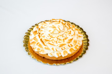 meringue and cream cake on a gold tray on white background