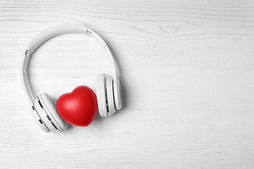 Headphones, heart and space for text on white wooden background, top view