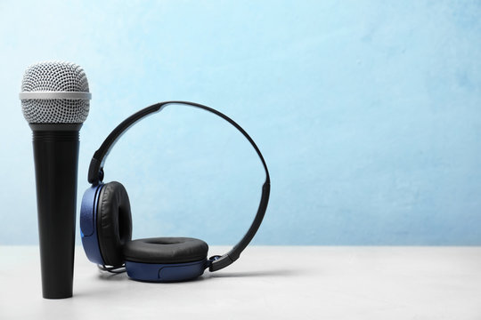 Headphones and microphone on table against color background. Space for text