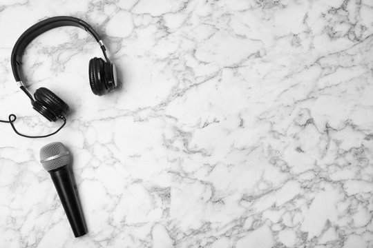 Headphones, microphone and space for text on marble background, top view