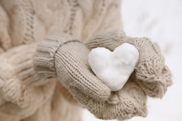 Woman holding heart made of snow, closeup view