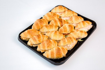 stuffed croissants on a black tray with white background