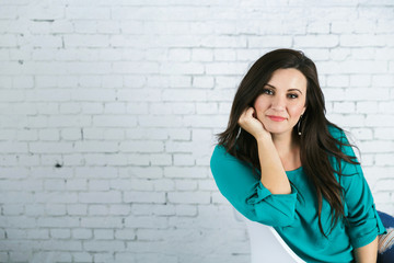 Beautiful Hispanic Woman Sitting Against White Brick Wall