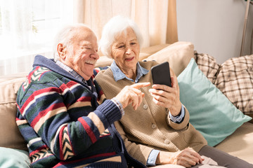 Portrait of adorable senior couple using smartphone together video chatting with family at home, copy space - Powered by Adobe