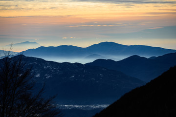 Obraz premium Beautiful view of some mountains surrounded by clouds and fog during sunset. National Park of Abruzzo, Lazio and Molise, Italy.