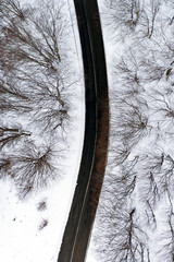 Aerial view of a road surrounded by pine trees forest and white snow. National Park of Abruzzo,...