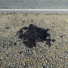 The piece of fresh asphalt which dropped out on a roadside