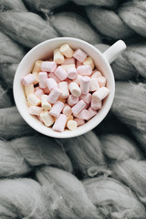 Fototapeta na wymiar Delicious sweet marshmallows in white cup on knitted plaid