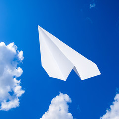 White paper airplane in a blue sky with clouds. The message symb