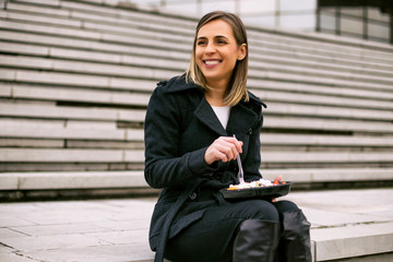 Beautiful businesswoman enjoys resting on a lunch break while sitting on the staircase in the city.