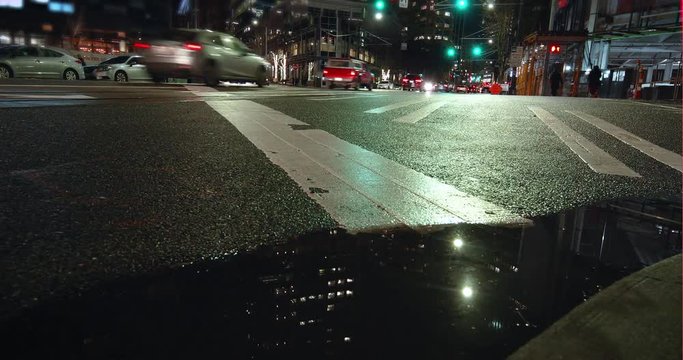 Low Puddle Timelapse of People Walking and Driving in Busy City Intersection at Night