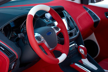 Steering wheel. Car dashboard. Car interior details. Red and black alcantara with stitching