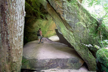 Photographer walking through moss covered cave in canyon