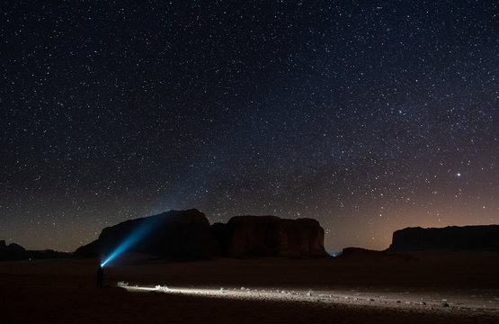 Explorer in desert at night with starry sky in Wadi Rum desert, Jordan
