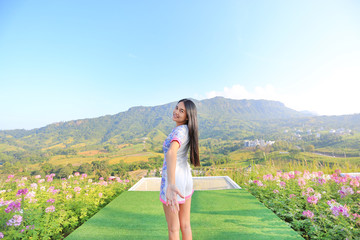 Half length of young Asian woman feeling free with arms wide open at beautiful trees and mountains on blue sky with morning sunlight.