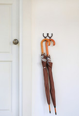 Obraz premium Umbrellas hanging in front of wood door room. Ready to be picked up during rain.