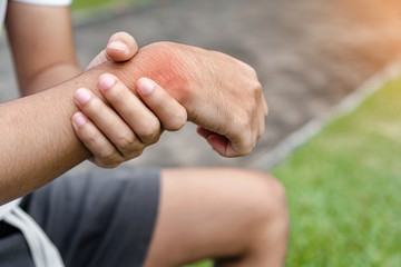 Young man asian have accident and holding him wrist pain twist sprain in sport exercise jogging, selective focus.