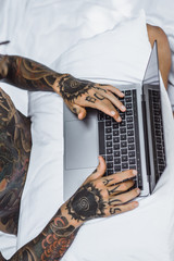 a man in bed working on a laptop, checking mail, watching a movie, listening to music, talking on...