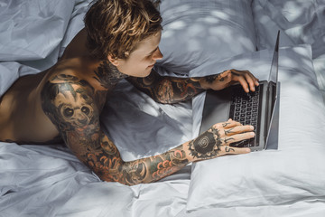 a man in bed working on a laptop, checking mail, watching a movie, listening to music, talking on...