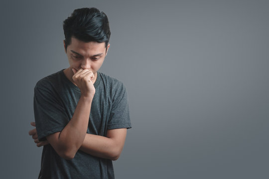 Young asian man sad with gray t-shirt isolate on dark background, With clipping path, Emotion concept.