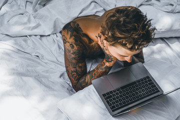 a man in bed working on a laptop, checking mail, watching a movie, listening to music, talking on...