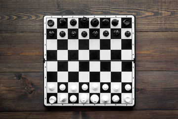 Chess game concept. Chess board with figures on dark wooden background top view copy space