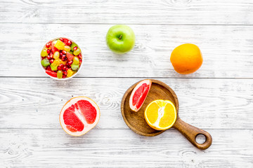 Food rich by vitamins and fiber. Healthy food. Fruit salad near fresh fruits on white wooden background top view