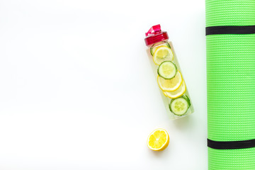 Healthy fruit water for sport, fitness. Bottle of water with lemon and cucumber near sport equipment on white background top view copy space