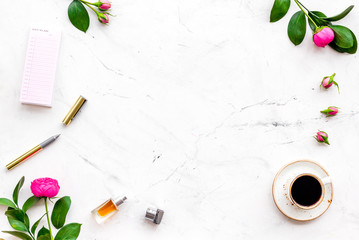 Home work desk, feminine workplace. Notebook and stationery near pink flowers and coffee on white background top view copy space frame