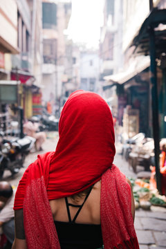 Woman wearing red headscarf walking along street, Varanasi, India
