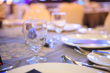 Blur background, Wine glasses, cutlery plates are beautifully placed on the dining table.