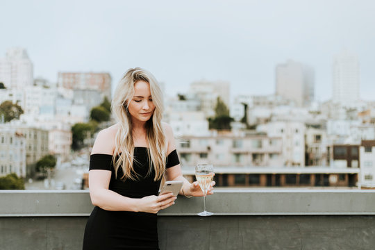 Bored Woman Using Her Phone At A Rooftop Party