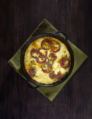 omelet with sausage and onions in a pan on a wooden background. top view. rustic style.