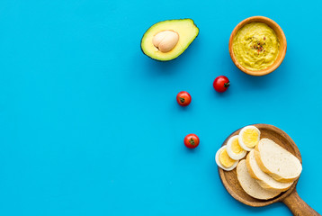 Sandwiches with avocado concept. Whole grain bread, half of avocado, guacamole on blue background top view copy space