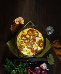 omelet with sausage and onions in a pan on a wooden background. top view. rustic style.