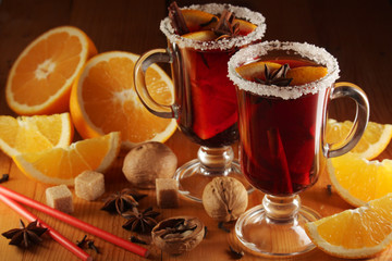 Two cups with ready mulled wine with anise, cinnamon and nuts around	