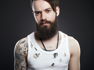 Brutal bearded hipster in vintage torn dirty shirt