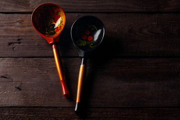 Wooden spoons with floral ornament in traditional folk Russian Khokhloma style on wooden table.
