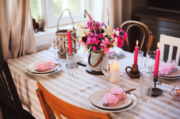 summer cottage kitchen decorated for festive dinner. Romantic table setting with candles and flowers in rustic style.