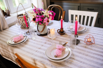 details of summer festive table with candles and seasonal flowers. Table setting for romantic dinner in cozy country house