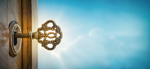Old key in keyhole on sky background with sun ray . Concept, symbol and Idea for History, business,...