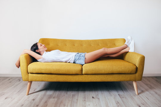 Happy young woman relaxing on couch at home