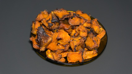 pieces of baked sweet pumpkin on a plate, on a black background
