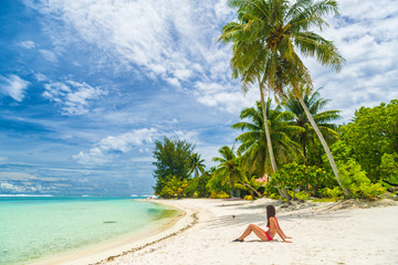 Relaxing woman sunbathing lying in sand on beach in bikini on Bora Bora Tahiti