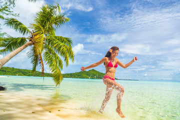 Travel Vacation beach woman laughing having fun splashing in water in paradise