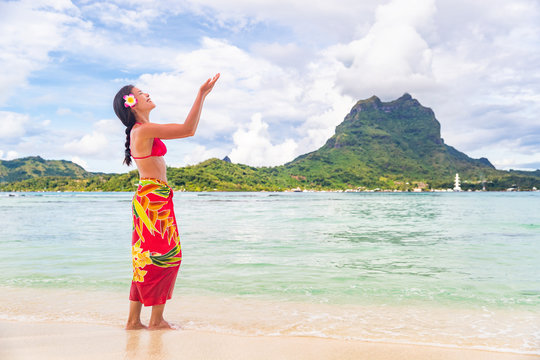 Polynesian hula dancer woman dancing on Bora Bora beach Hawaii traditional dance for luau party. Happy Asian tourist learning to dance in front of Mt Otemanu, Tahiti, French Polynesia.